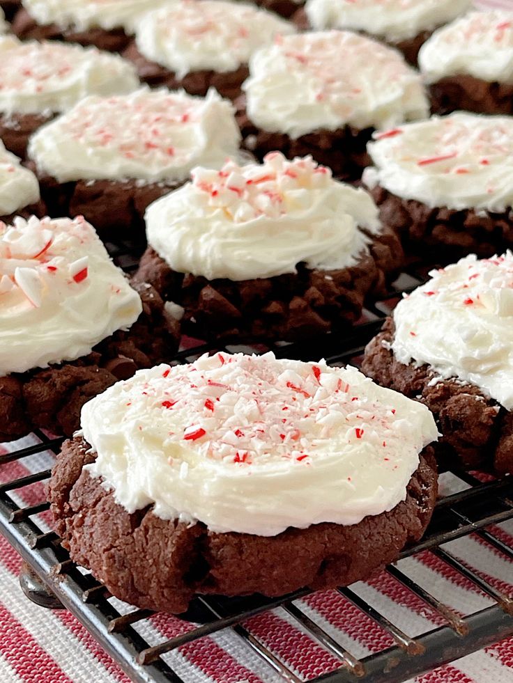 chocolate cookies with white frosting and sprinkles on a cooling rack