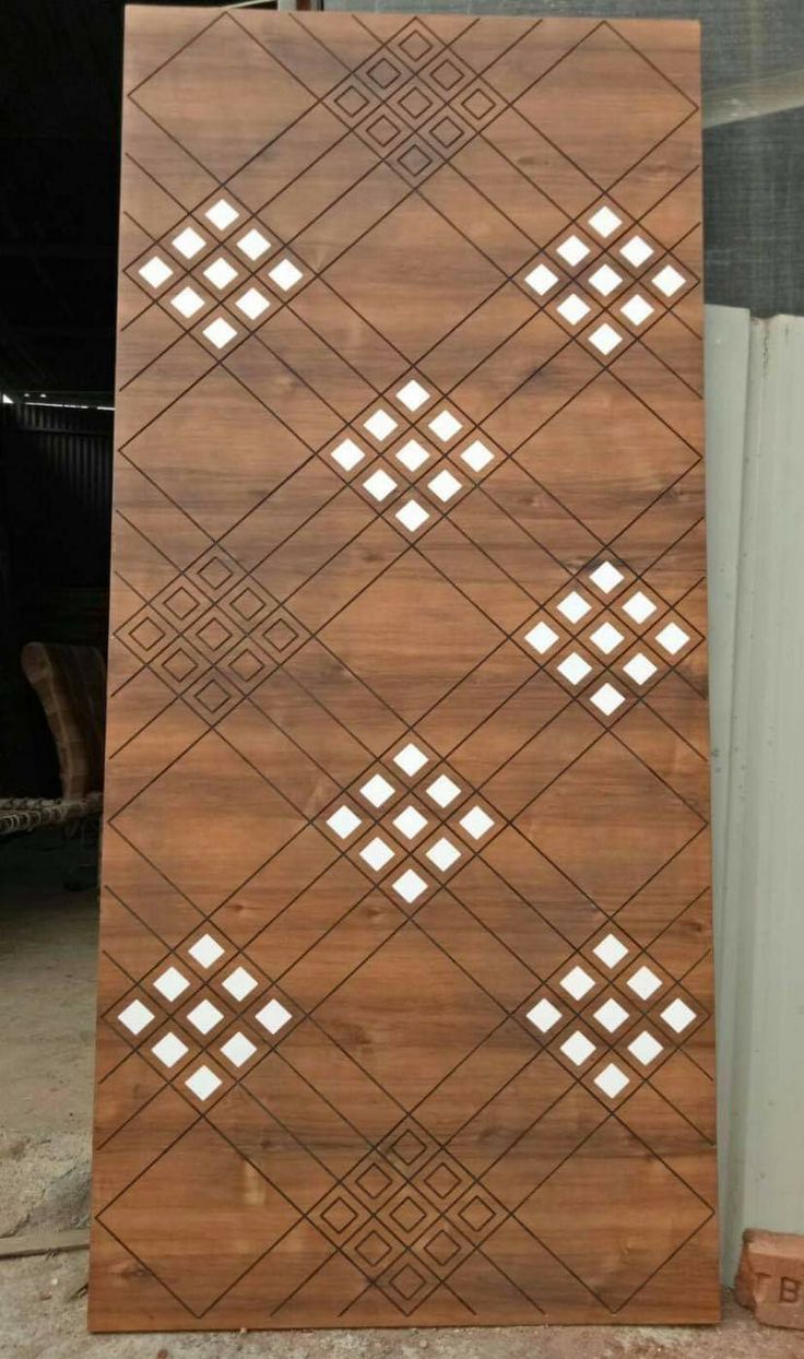 a wooden board with geometric designs on the front and sides, sitting next to a building