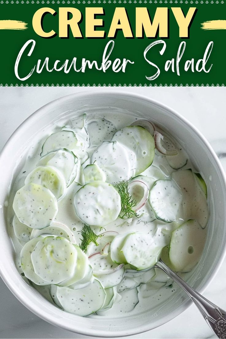 a white bowl filled with cucumber salad on top of a table next to a spoon