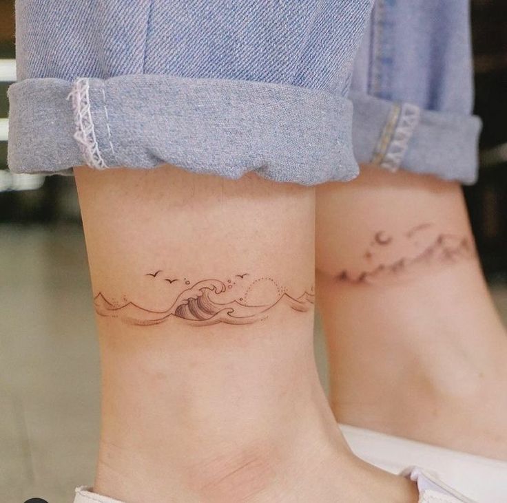 two people with matching tattoos on their feet, one has a wave and the other has a bird