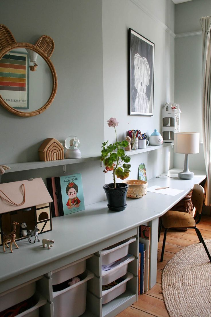 a room with a desk, bookshelf and pictures on the wall