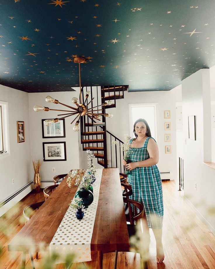 a woman standing in the middle of a dining room with stars painted on the ceiling