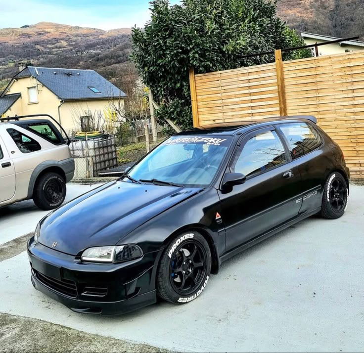 a black car parked in front of a wooden fence