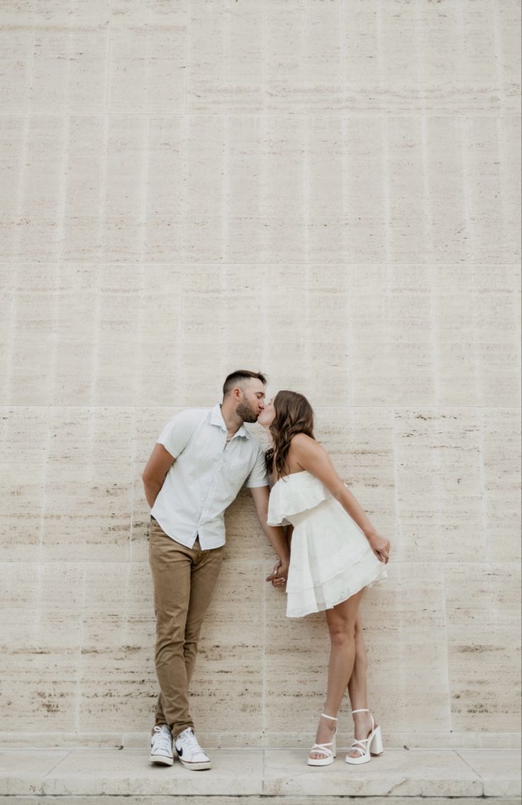 a man and woman kissing in front of a wall