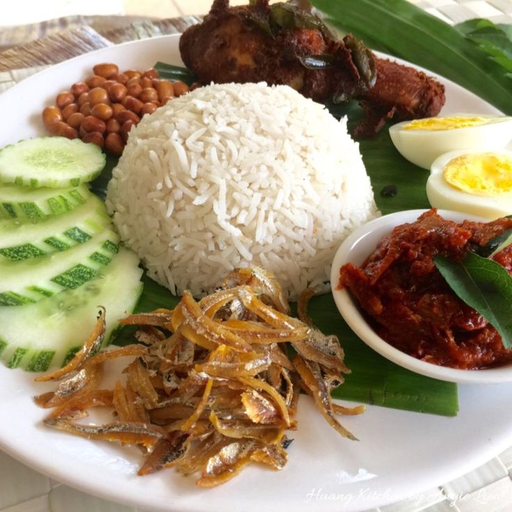 a white plate topped with rice, meat and veggies next to an egg