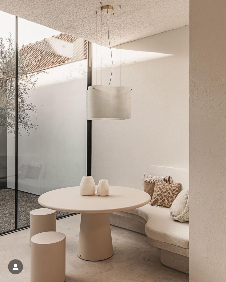 a white table sitting in the middle of a living room next to a wall with glass doors