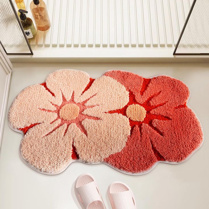 a pair of slippers sitting on top of a bathroom floor next to a flower rug