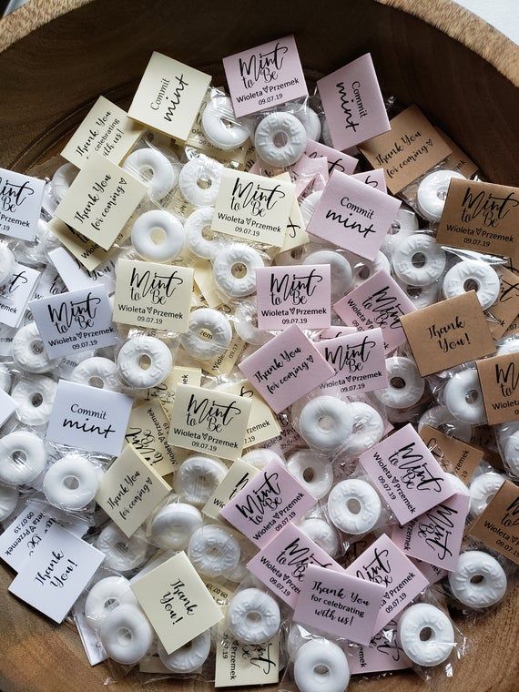 a wooden bowl filled with white donuts covered in pink and white icing labels