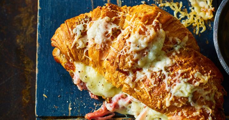 a piece of bread with meat and cheese on it next to a bowl of pasta