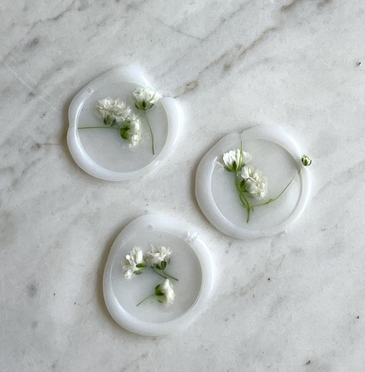 three white plates with flowers on them sitting on a marble counter top, next to each other