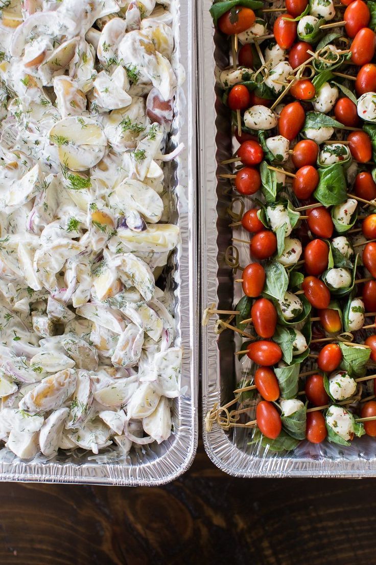 two trays filled with different types of food and vegetables on skewers next to each other