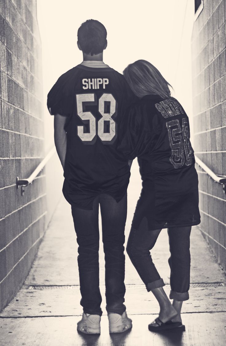 a man and woman walking down a hallway with their back to the camera, both wearing shirts that say ship