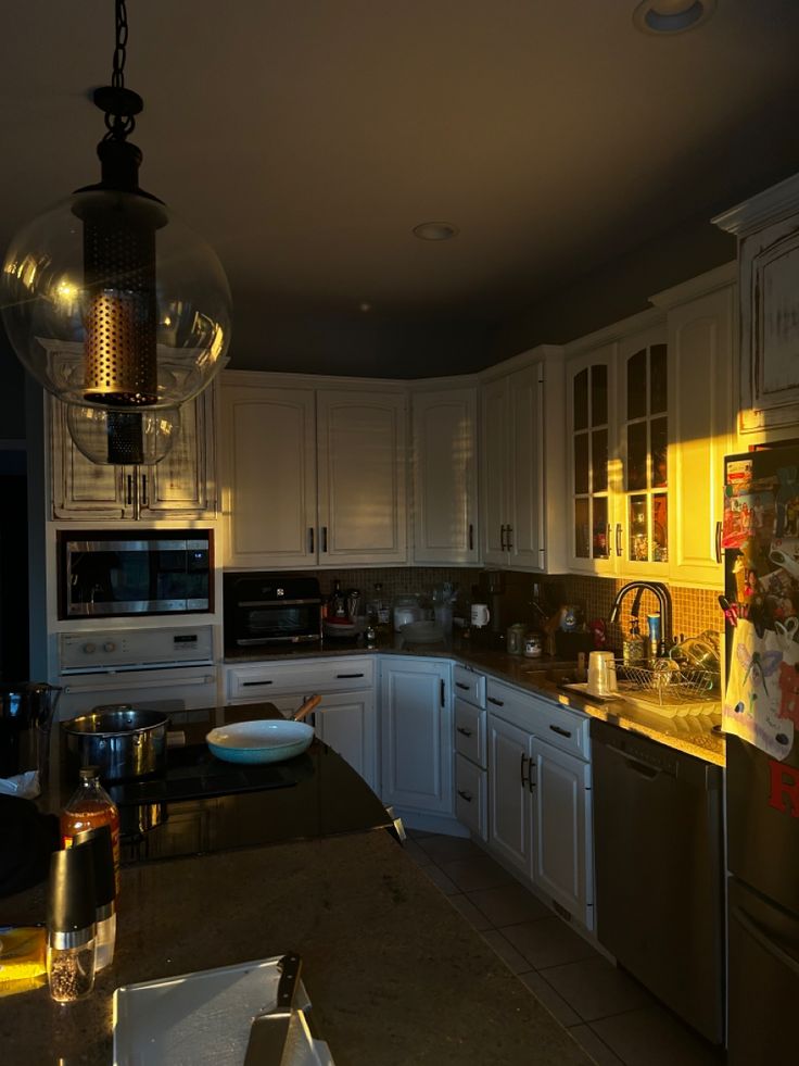 a kitchen with white cabinets and stainless steel appliances, is lit by the sun's light