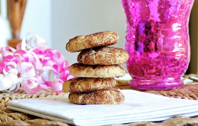 a stack of cookies sitting on top of a white napkin next to a pink vase