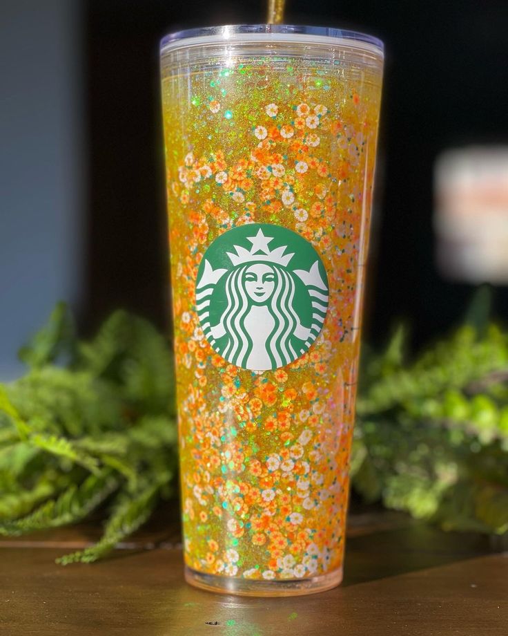 a starbucks cup with orange sprinkles and a green straw sticking out of it