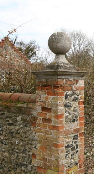 an old brick fence with a stone ball on top