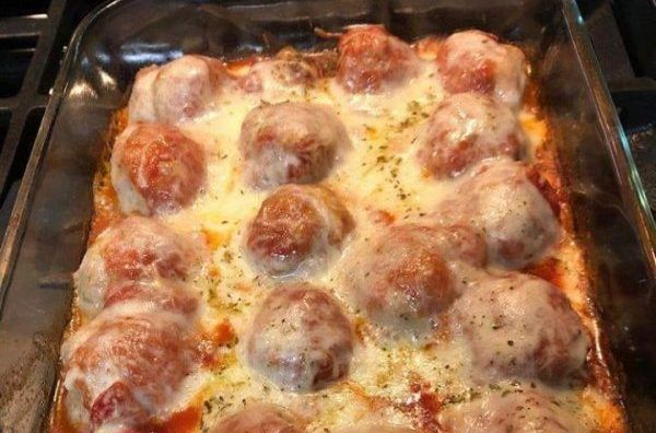 a pan filled with meatballs and cheese on top of a stove