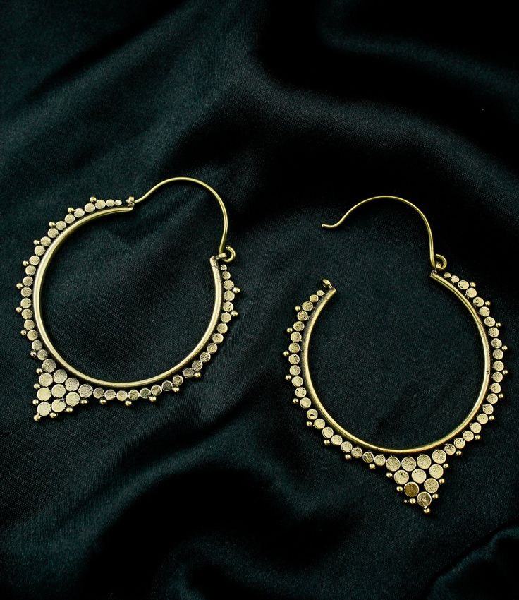 two pairs of gold hoop earrings sitting on top of a black cloth covered tablecloth