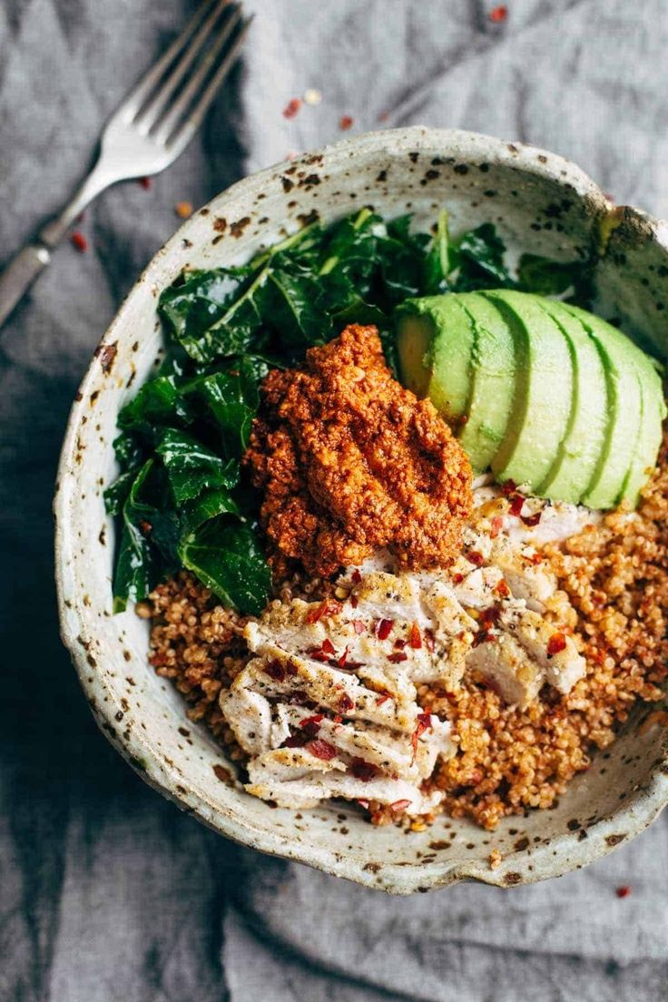 a bowl filled with meat and vegetables on top of a table next to a fork