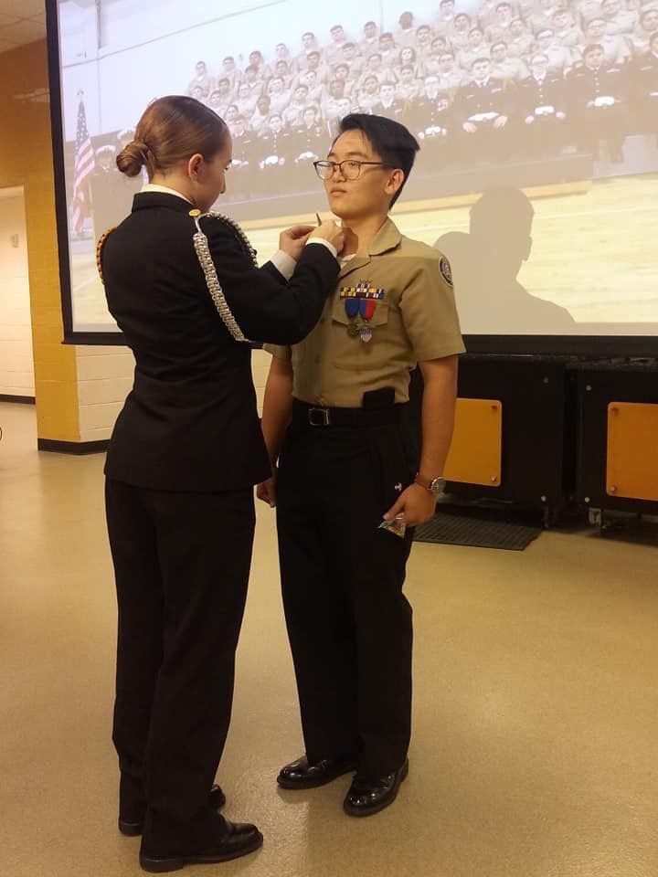 two people standing in front of a projector screen and one is fixing the tie