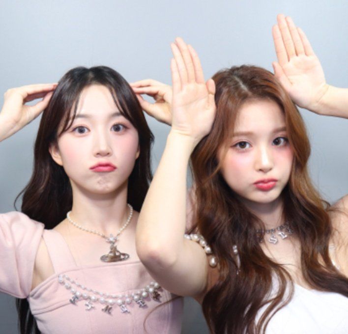 two young women are posing for the camera with their hands on their head and one is holding her hair