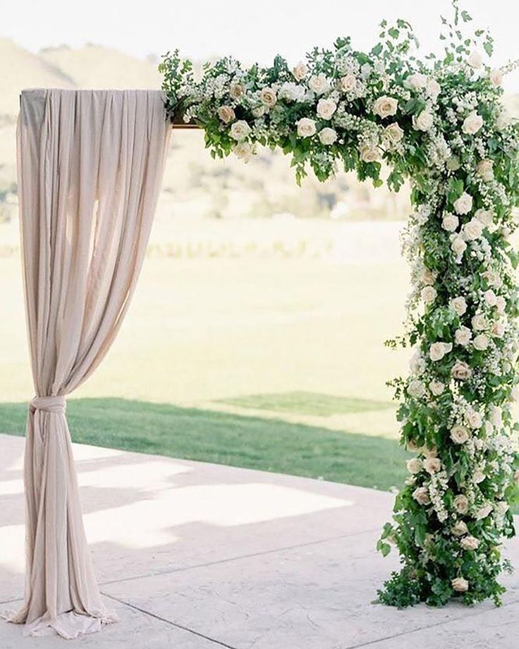 a wedding arch decorated with white flowers and greenery