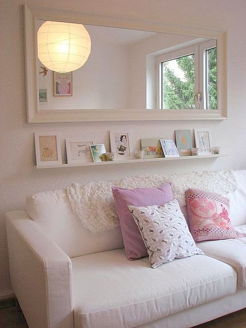 a white couch sitting under a mirror in a living room