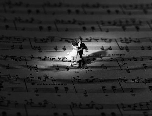 a small figurine on top of sheet music with musical notes in the background