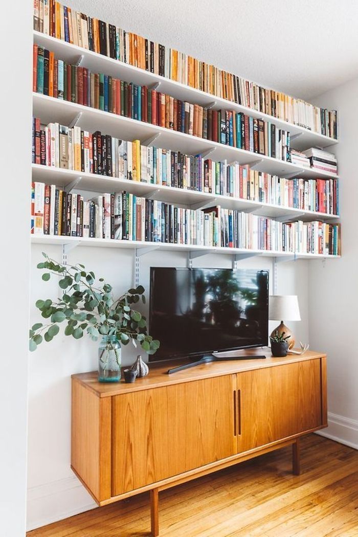 a television sitting on top of a wooden cabinet in front of a bookshelf