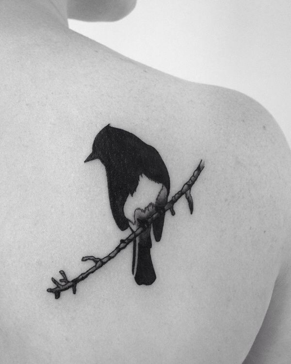 a black and white photo of a person with a bird tattoo on their back shoulder