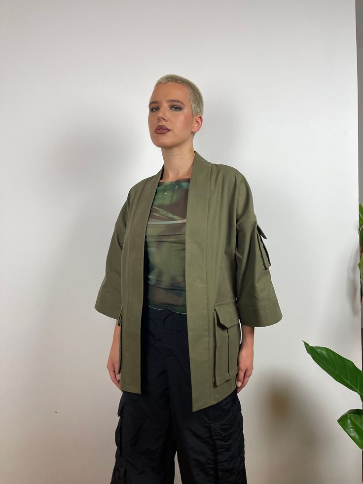 Khaki green Kimono with utility-style cargo pockets. The oversized design is great for layering over jackets, coats and jumpers. It is designed with  ¾ length sleeves and an open front. Made from high-quality sanded canvas from a historic UK company. All fabrics used are 100% plastic-free. This item comes in XS, S, M and L sizes. Please specify which size you would like upon purchase. Made in East London, UK. Oversized Khaki Outerwear With Flap Pockets, Olive Utility Outerwear With Patch Pockets, Oversized Khaki Outerwear With Pockets, Oversized Military Outerwear With Pockets, Oversized Utility Jacket With Multiple Pockets, Oversized Utility Outerwear With Pockets, Oversized Khaki Outerwear With Patch Pockets, Oversized Khaki Utility Jacket With Multiple Pockets, Oversized Techwear Outerwear With Pockets