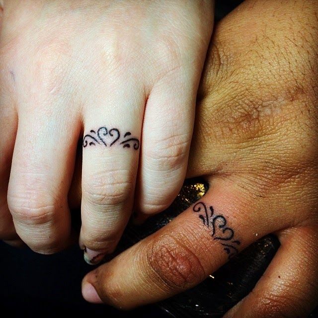 two people holding hands with tattoos on their fingers