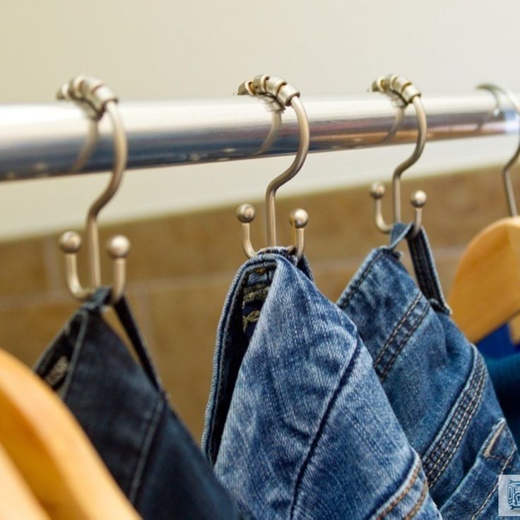 several pairs of jeans hanging on clothes racks