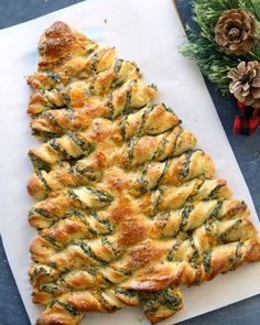 a pastry shaped like a christmas tree sitting on top of a cutting board next to pine cones