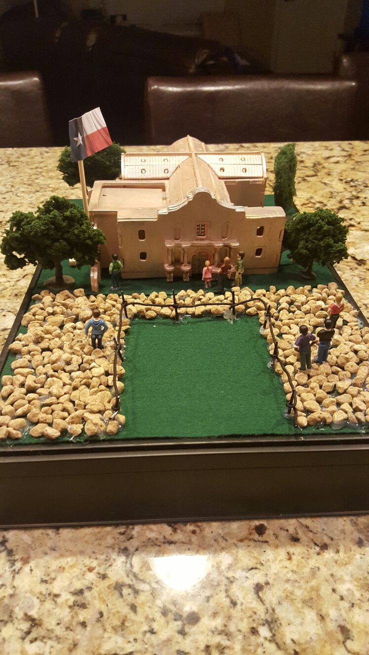 a model of a house with rocks and grass in the foreground on a table