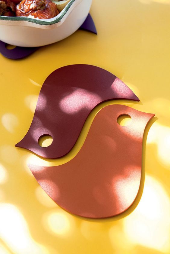 two birds sitting on top of a yellow table next to a bowl of fruit and vegetables