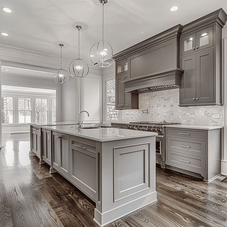 a large kitchen with wooden floors and gray cabinets on the walls, along with an island in the middle