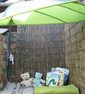 there is a green umbrella and some stuffed animals in the sand under an open umbrella