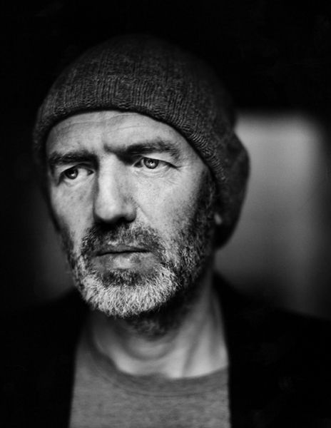 a black and white photo of a man in a beanie looking at the camera