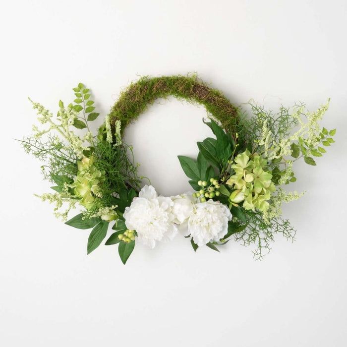 a green wreath with white flowers and greenery