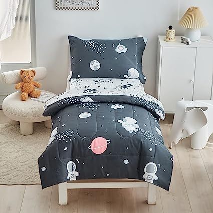 a child's bed in a white room with space themed sheets and comforter