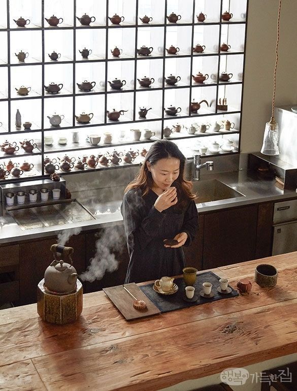 a woman standing in front of a wooden table with pots and pans on it