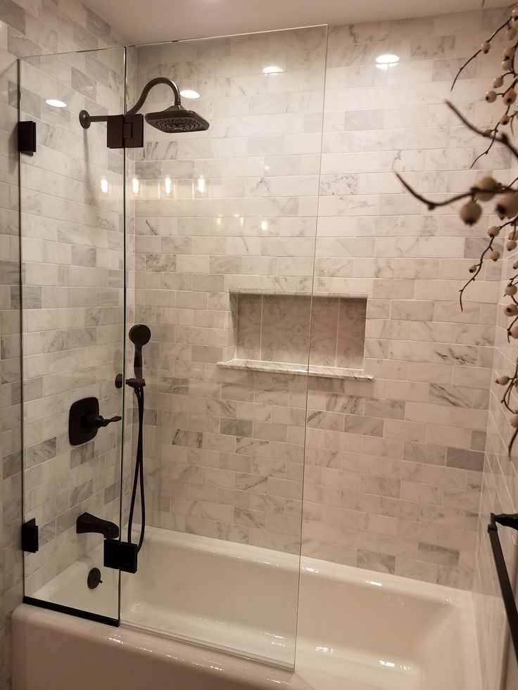 a bathroom with a tub, shower and tiled walls