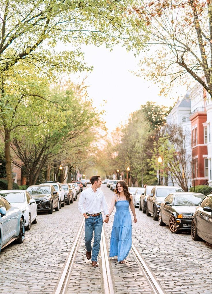 an engaged couple walking down the street holding hands