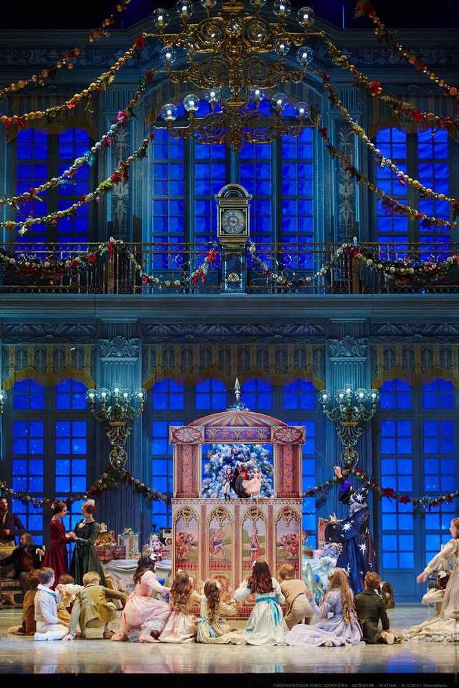 a group of people sitting on top of a stage in front of a building with blue windows