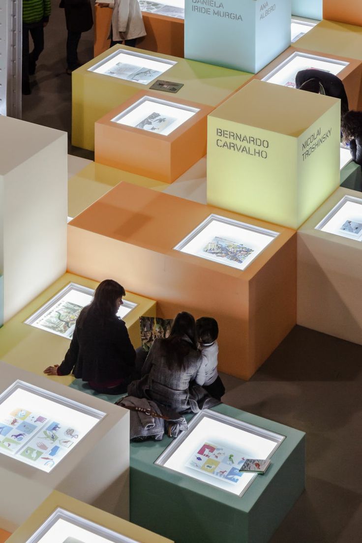 two people sitting on the ground in front of many lit up boxes that are all different colors