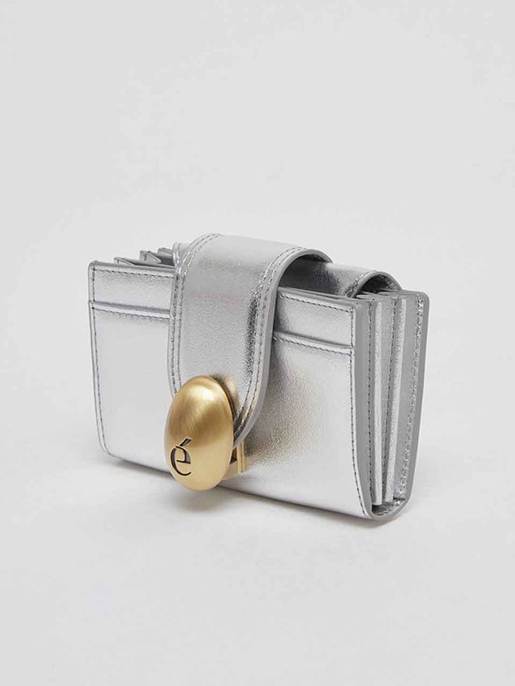 Pursuing an Effortlessly Cool Attitude that breaks down the boundary between cool and comfort, Archivepke proposes stylish items with no distinction between Workweek and Weekend based on simple and classic essential items, soft leather with a flexible texture, and various styles and harmonious color tones.  - Egg shape metal lock decoration with engraved 'e' logo- Bold and modern mood mini wallet- Compact mini size yet great to store small essentials- Accordion style wallet for practical storage Luxury Leather Wallet With Silver-tone Logo, Luxury Leather Wallets With Silver-tone Hardware, Luxury Leather Wallet With Silver-tone Hardware, Designer Silver Wallet With Card Slots, Modern Wallets With Magnetic Closure, Silver Bifold Wallet For Formal Occasions, Silver Leather Evening Wallets, Evening Silver Leather Wallets, Silver Leather Wallets