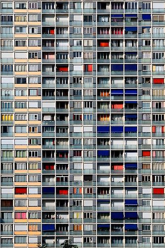 multicolored apartment building facade with windows and balconies in the window panes