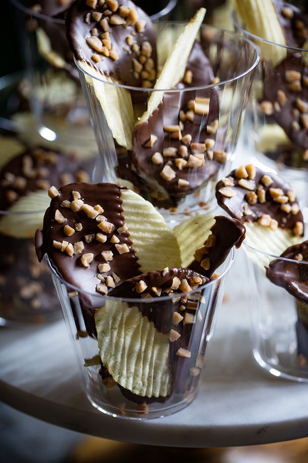 chocolate covered bananas and nuts in cups on a silver platter with other desserts