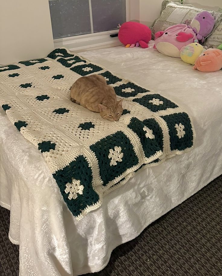 an orange cat laying on top of a white bed